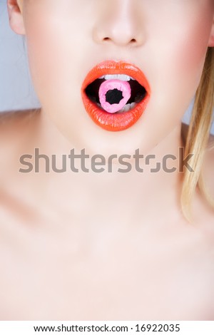 Woman orange lips biting on pink candy ? close-up