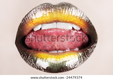 macro of woman sticking her tongue with black glossy lipstick and gold powder shine