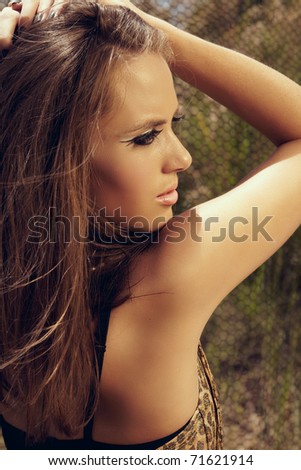 beautiful young woman with long brown hair wearing leopard print dress and cat eye fashion make-up with false lashes, shot outdoors in the middle of the day for saturated summer look.