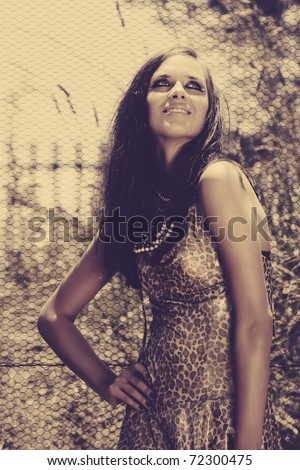 beautiful young woman with long brown hair wearing leopard gold print dress and cat eye fashion make-up in retro seventies effect