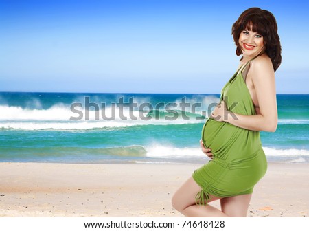 beautiful pregnant woman in green dress against summer sea and blue sky background - concept of travel in pregnancy.