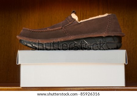stylish brown suede fur man\'s shoe on a box in a wooden shelf display with copy space.