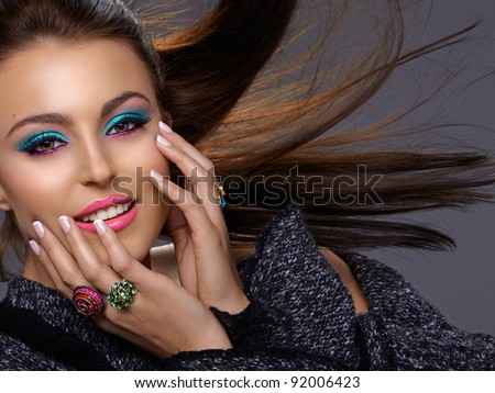 beautiful Italian young oman with fashion bright make-up smiling with hair blowing in the wind.