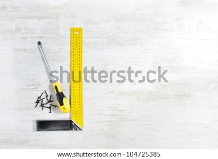 Screwdriver with screw and ruler. Tools set for construction work over wooden background.