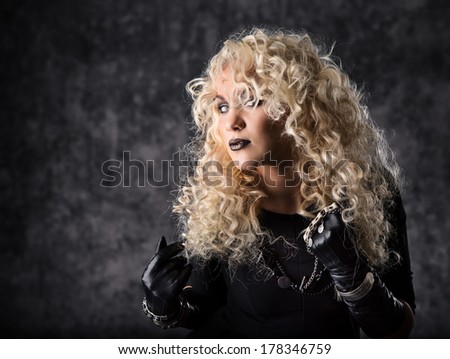 Woman blonde curly hair, beauty portrait in black rock style over dark background