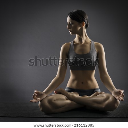 Yoga woman meditate sitting in lotus pose. Silhouette of exercise girl over black background.