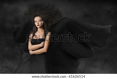 Mysterious woman in black dress and flying wings and hairs. gothic style make up