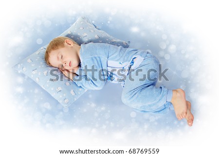 Child sleeping on pillow in sleepwear. Magic blue background
