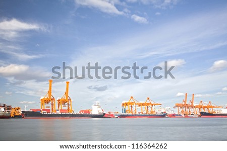 Cargo Ships Loading and unloading goods container with cranes at Port Terminal with beautiful cloudscape for heavy industry and logistic background