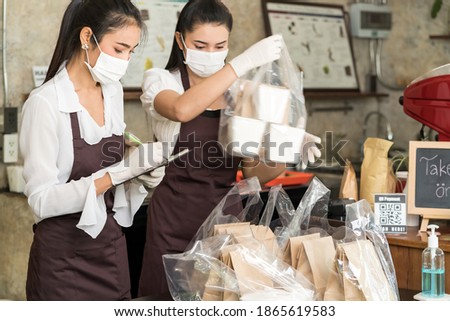 Asian waitress wear protective face mask prepare food for takeout and curbside pickup orders while city lockdown from coronavirus COVID-19 pandemic. This is essential service while lockdown.