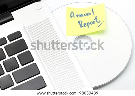 White laptop with Business Annual Report dvd disk in slot-loading drive on a white background.