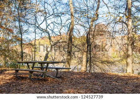 An empty picnic table in a wooded park by a river in winter