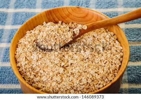 Fresh oats in a wood bowl with a wood spoon