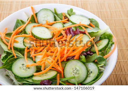 Fresh salad in white bowl of lettuce, greens, spinach, arugula, cucumbers, carrots