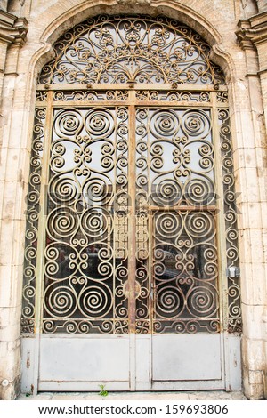 An old rusty metal door of glass and scroll work
