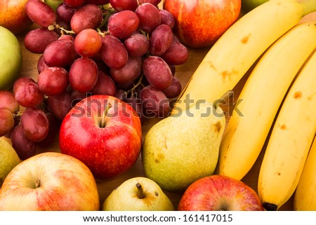 Closeup of fresh bananas, pears, apples and grapes on a wood table