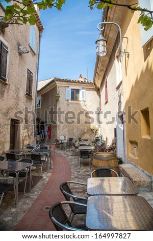 Tables outside a restaurant in a narrow Eze alley
