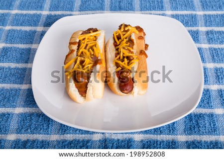 Two Chili Cheese Dogs on a white plate