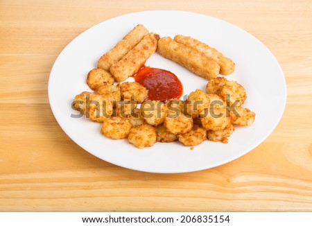 White plate with fried fish sticks and potato puffs with cocktail sauce