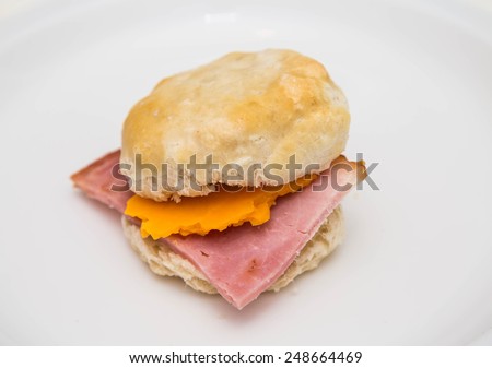 A fresh, hot ham and cheese biscuit on a white plate