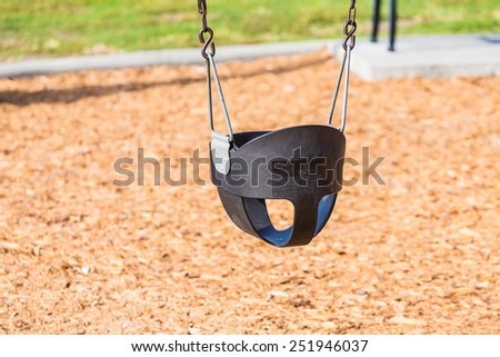 A single plastic safety swing in a park over wood chips