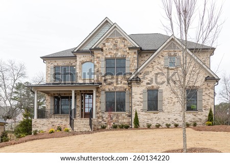 A new brick home on a landscaped hill in winter