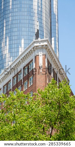 An old red brick apartment building in front of a modern, round blue glass tower
