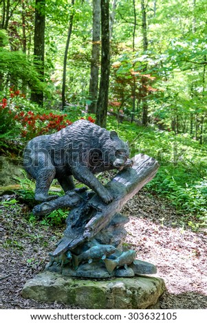 A statue of a bear on a log with fish in a natural green setting