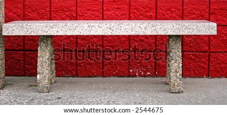 Empty concrete bench in front of red block wall