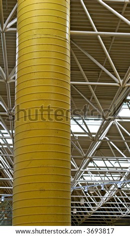 An industrial view of a yellow metal column in a white steel building