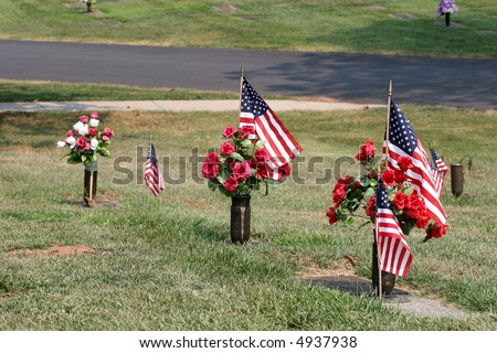 Flowers and American flags along grave sites at a cemetery