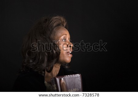 A black woman with bible in hand singing hymns