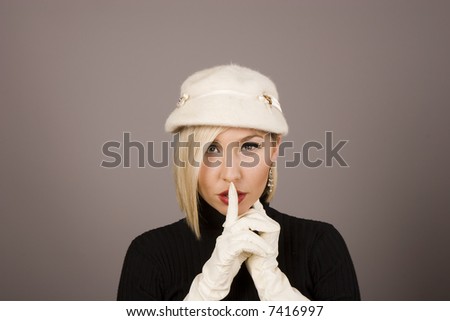 A blonde fashion model in white hat and gloves saying hush