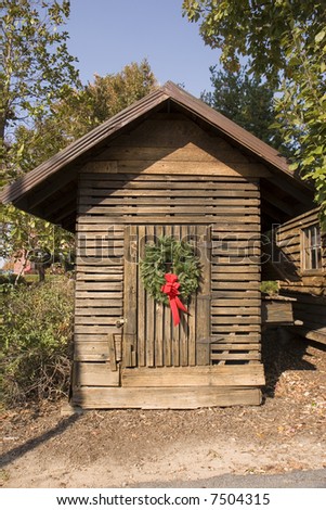 An old wooden shack with a Christmas Wreath on the door