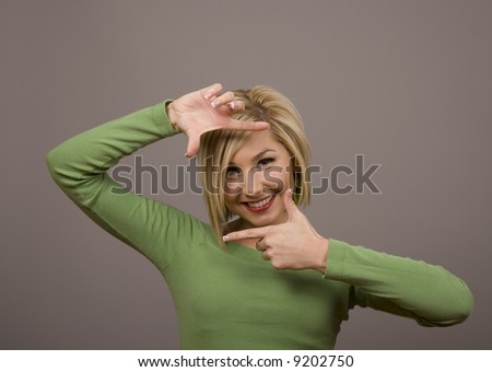 A blonde fashion model in green blouse framing her face with her hands