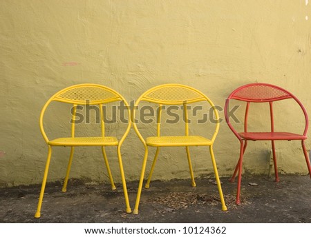 Old red and yellow chairs against a cracked yellow wall
