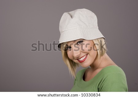 A blonde in a green blouse and white hat smiling for the camera