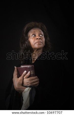 A black woman holding a bible with a heavenly light on her face