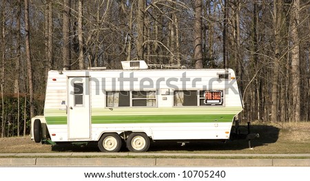 A yellow and green camper trailer on the side of the road with a for sale sign in the window