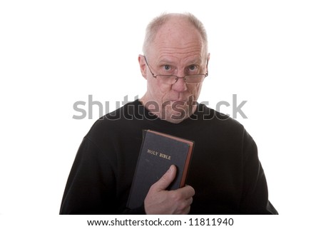 An older guy in a black shirt on a white background holding a bible