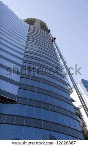 A modern curving blue glass office tower shot from below