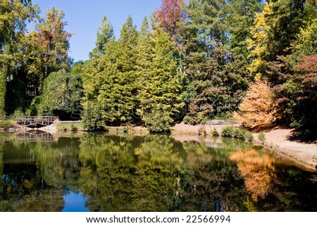 An old bridge and trees changing in the fall reflected in a calm lake
