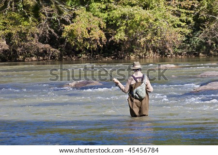 A fly fisherman casting a line in the river