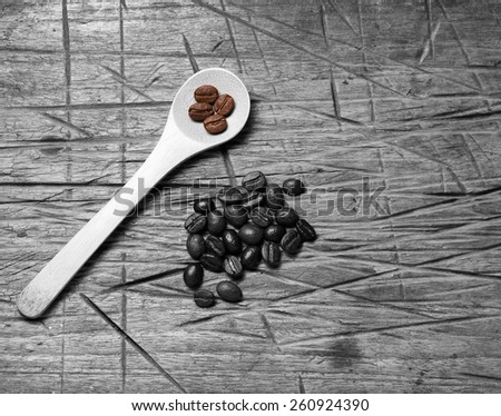 Coffee crop beans on bamboo spoon and wooden texture background