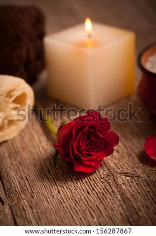 Spa arrangement with red rose and white candle on wood background