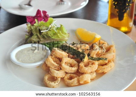 Seafood - Fried Calamari. Deep-fried Squid Dressed with Salad Leaves, Parsley, Olives and Lemon. Isolated on White Background