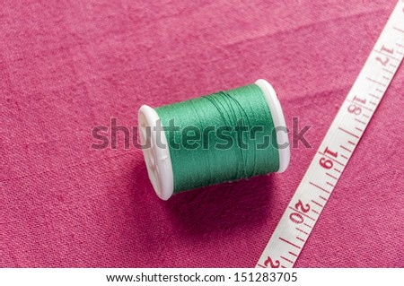 cotton reel and meter tape on cotton textile background