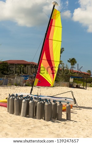 Scuba tanks on the beach beneath a colorful sail