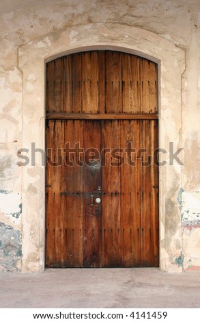 A weathered door made of distressed wood with a lock.