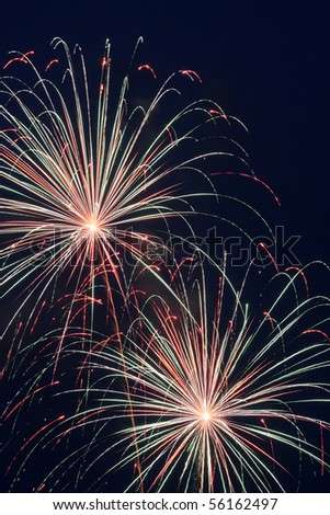 Two red, white, and blue firework bursts in a night sky on the Fourth of July